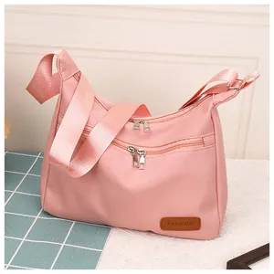 Detail of pink waterproof crossbody dumpling bag showing multiple zipper pockets and fabric
