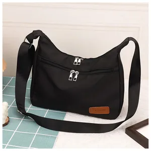 Detailed macro view of black nylon dumpling bag featuring dual zippers and fashion logo