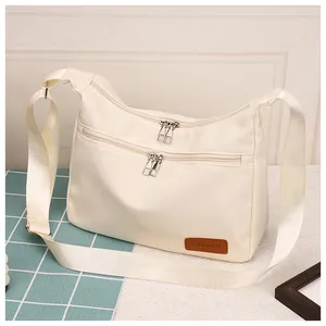 Detail of off-white waterproof shoulder bag showing multi-zip layers and textured fabric