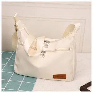 Detail of off-white waterproof nylon dumpling bag with two zipper pockets and leather tag