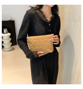 Detail of khaki quilted handbag with 3D floral pattern held by a model in black lace