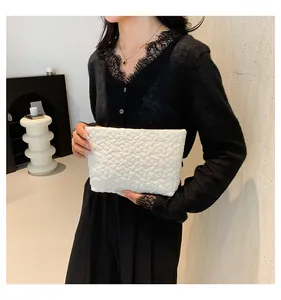 Close-up of elegant white minimalist clutch bag with 3D floral texture and soft fabric