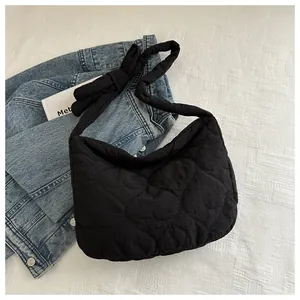 Detail of heart-quilted black shoulder bag with a stylish knotted padded strap design
