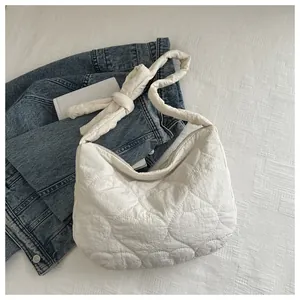 Detail of white quilted heart pattern canvas bag with adjustable bow on shoulder strap