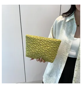 Detail of green floral quilted clutch bag with soft puffed texture for daily use
