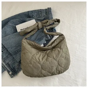Detail of green heart-shaped quilted pattern and soft shoulder strap on canvas tote bag