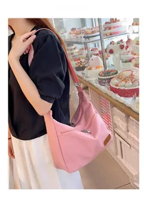 Detailed shot of pink nylon crossbody bag with zipper pockets and leather brand logo