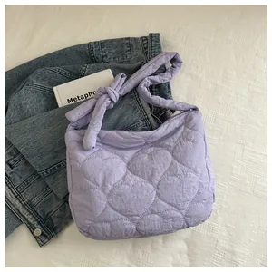 Detail of lavender quilted shoulder bag featuring heart patterns and knotted strap design