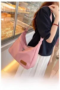 Detail of pink waterproof crossbody hobo bag with leather fashion tag and adjustable strap