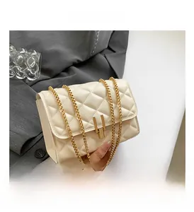 Close-up of cream quilted crossbody bag with gold U-shaped buckle and metal chain strap