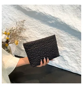 Close-up of black quilted clutch bag featuring elegant 3D floral texture and nylon fabric