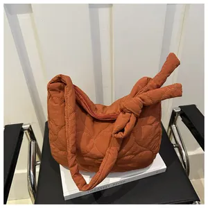 Close-up of caramel quilted canvas shoulder bag with decorative bow knot and zipper detail