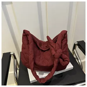 Close-up of wine red quilted hobo bag with knot strap detail on a minimalist setup