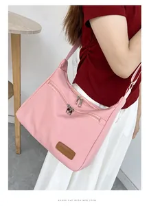 Detail of pink nylon crossbody bag with dual zipper pockets and fashion label on model