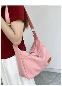 Pink nylon hobo bag featuring multiple zipper pockets and a brown leather fashion patch