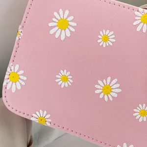 Detail of pink crossbody bag with white daisy print and premium cross-grain leather texture