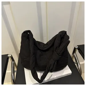 Detail of black quilted puffer bag with a unique decorative knot handle on the side