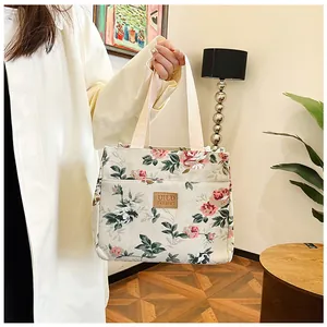 Detalle de la bolsa de almuerzo de lona con flores y etiqueta de cuero marrón