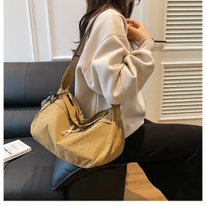 Detail van kaki nylon draagtas met verstelbare riem en zijvak op een model