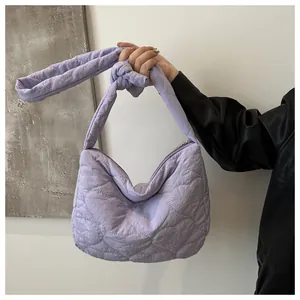 Detail of light purple quilted canvas shoulder bag with heart pattern and knot strap