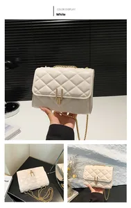 Detailed view of white quilted crossbody bag with gold metal chain and twist lock closure