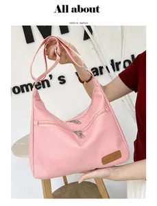 Detail of pink waterproof crossbody bag featuring front zipper pockets and leather tag