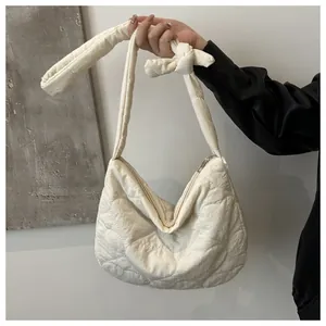 Detail of cream quilted hobo bag with heart patterns and adjustable knotted shoulder strap