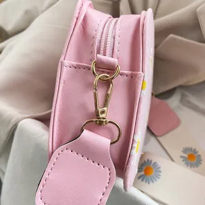 Close-up of pink leather crossbody bag with daisy embroidery and gold-tone zipper