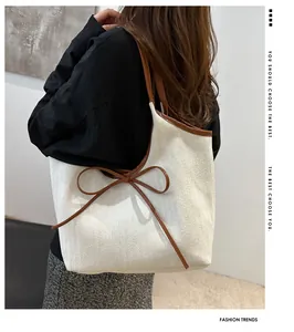 Detail of herringbone canvas tote bag with brown leather trim and bow tie decoration