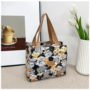 Detalle de bolsa de lona para almuerzo con estampados de gatos coloridos y asas marrones