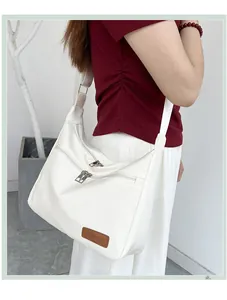 Close-up of white soft leather crossbody dumpling bag with wide strap and fashion label