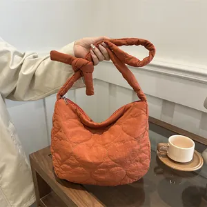 Chic brick red quilted shoulder bag with heart patterns and knotted strap detail