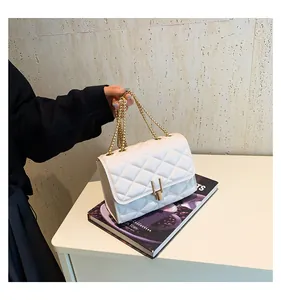 Close-up of white quilted crossbody bag with gold chain strap and U-shaped metal clasp