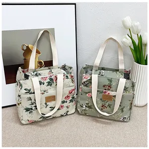 Detalle de bolsas de almuerzo de lona con flores, asas y bolsillos laterales