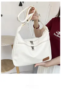 Detail of white nylon crescent bag with double zipper pockets and adjustable wide strap