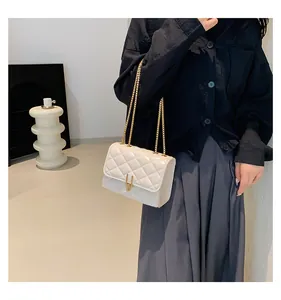 Close-up of white quilted leather bag with metallic gold lock and elegant chain strap