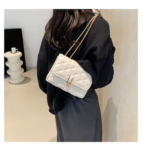 Close-up of ivory quilted chain bag with elegant gold metal latch and fine texture