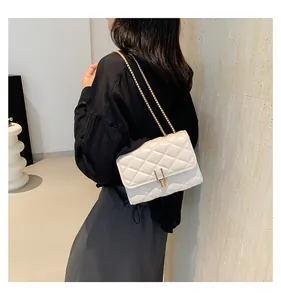 Detailed view of quilted white leather shoulder bag with gold chain and vertical lock