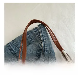 Detail of brown leather handles and herringbone fabric texture on a tote bag