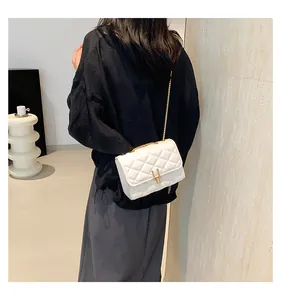 Close-up of a white quilted crossbody bag with a gold chain strap and U-shaped buckle