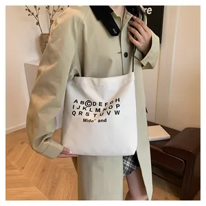Dettaglio della borsa tote in tela con tracolla nera e stampa alfabeto in stile lifestyle