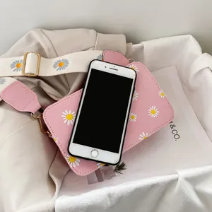 Detail of pink daisy print crossbody bag with smartphone showing internal capacity