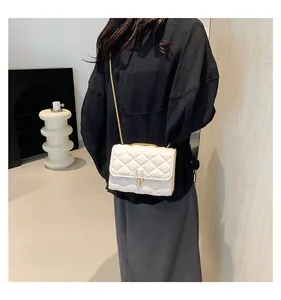 Close-up of white quilted crossbody bag with gold chain strap and metal lock detail