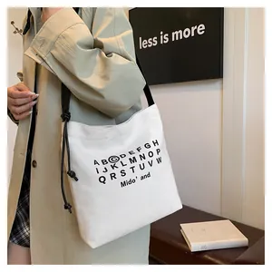 Dettaglio borsa tote in tela bianca con stampa alfabeto e sottili spalline sulla spalla
