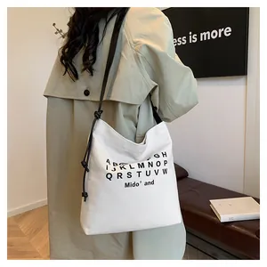 Dettaglio della borsa tote in tela bianco avorio con stampa alfabeto e tracolla annodata