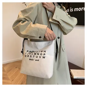 Dettaglio borsa tote grande in tela con stampa alfabeto e coulisse indossata da modella
