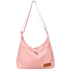 Pink waterproof nylon dumpling cross-body bag with adjustable shoulder strap and zippers