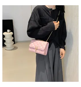 Close-up of pink quilted crossbody bag with golden metal bar lock and chain strap