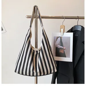 Vue détaillée du sac cabas en toile rayée suspendu à un cintre au style minimaliste