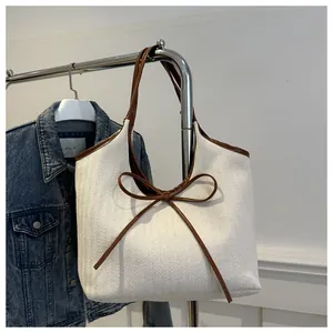 Macro detail of canvas tote bag with herringbone weave, bow accent and brown handles
